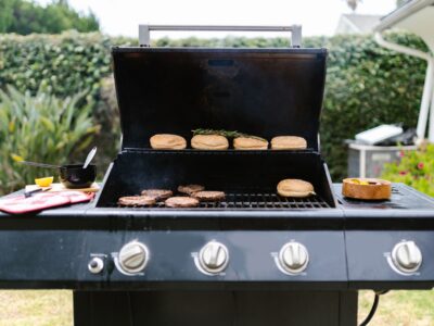 Outdoor barbecue grill with burgers and buns, perfect for summer cooking.